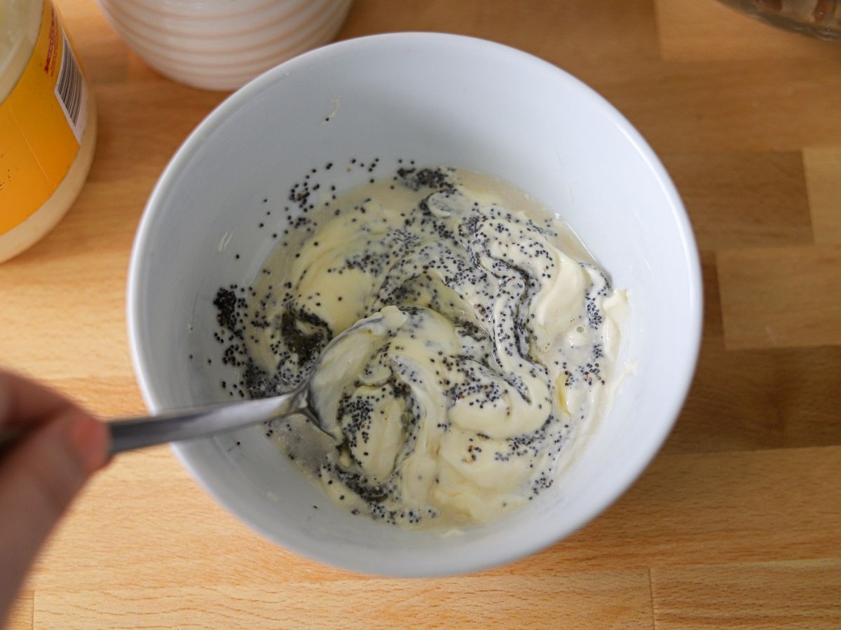 Mayonnaise, apple cider vinegar, honey, and poppy seeds being mixed together in a bowl for chicken salad.