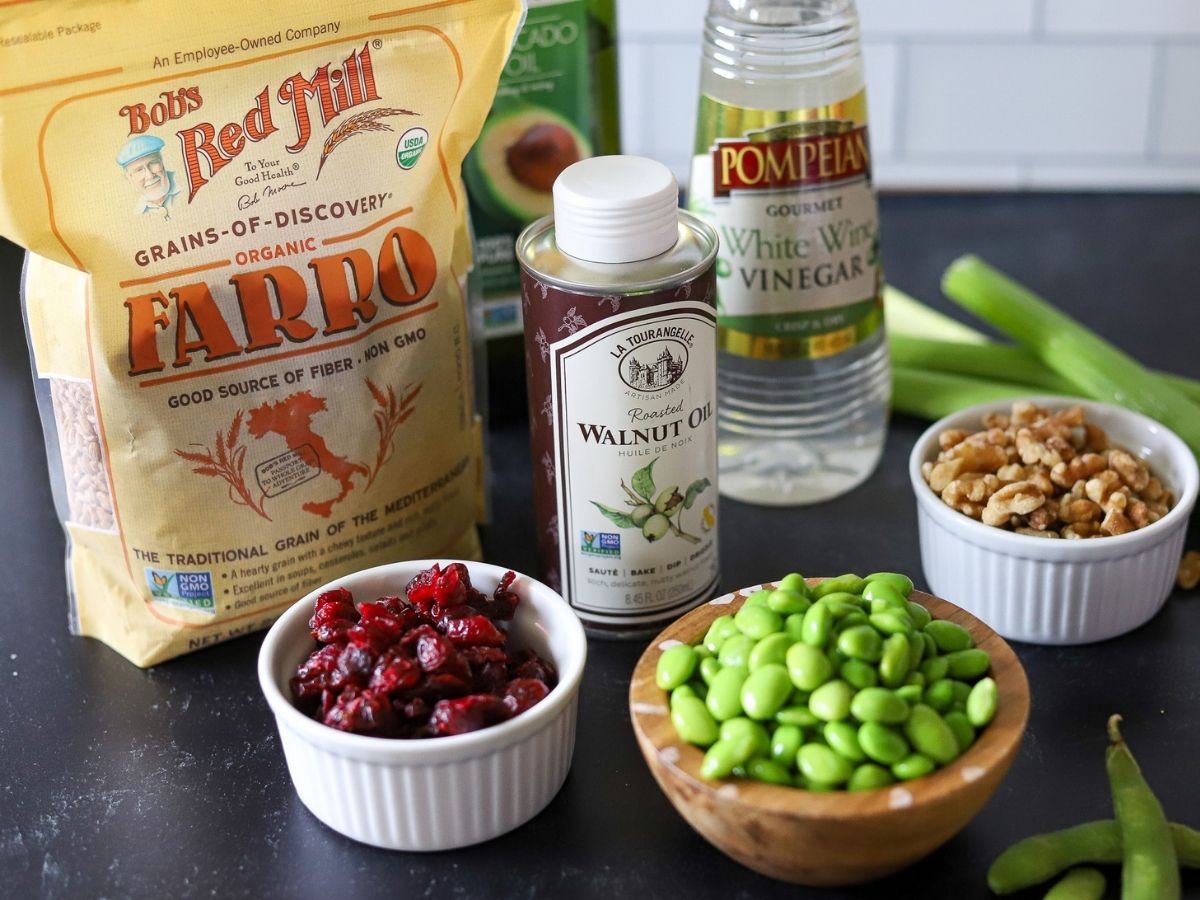 ingredients for farro salad including raw farro, walnut oil, walnuts, edamame, celery, and white wine vinegar