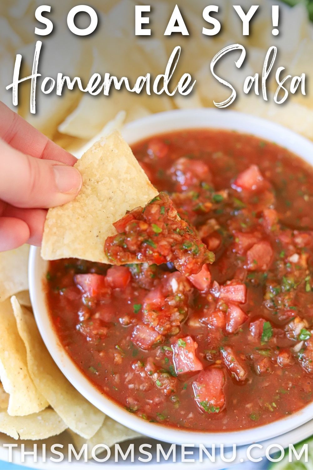 A white bowl full of homemade salsa with one tortilla chip being dipped into the salsa