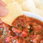 a tortilla chip being dipped into homemade restaurant style salsa