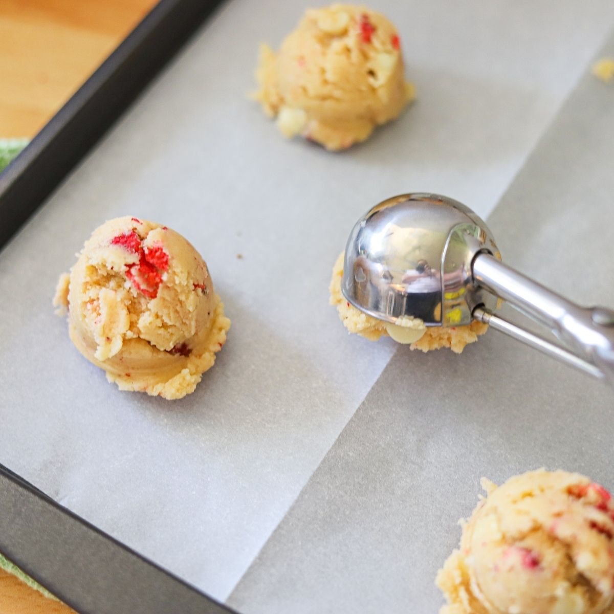 strawberry shortcake cookie dough being scooped onto a baking sheet.