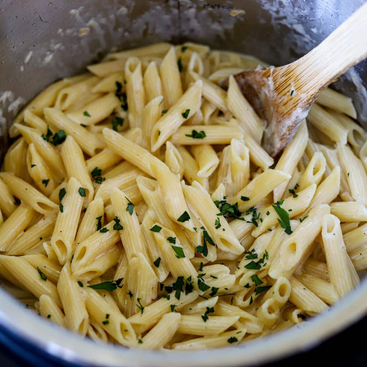Homemade pasta and Alfredo in an instant pot, garnished with chopped parsley