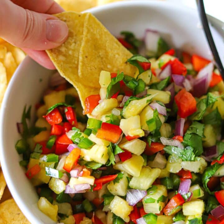 Pineapple salsa being scooped up with a tortilla chip