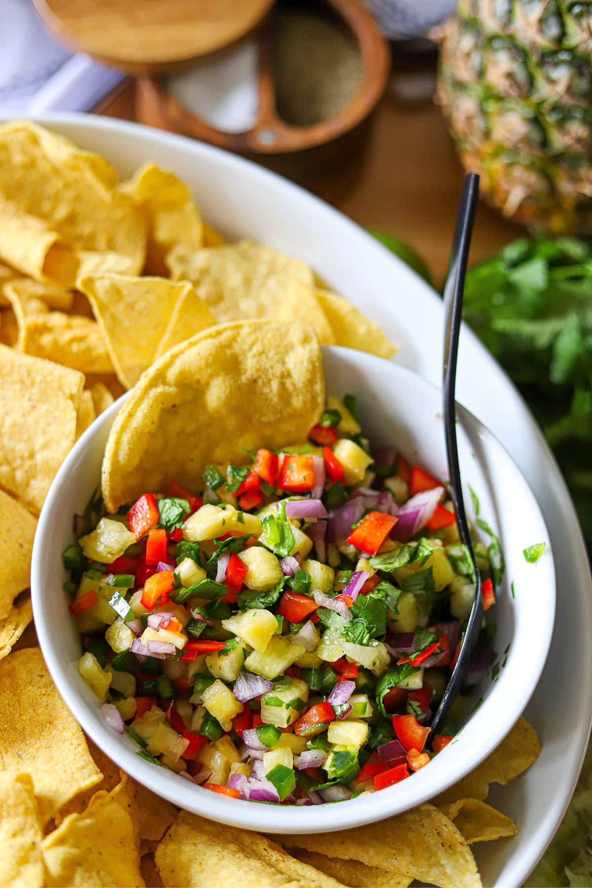 a bowl filled with pineapple salsa and surrounded by tortilla chips