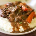 Pot roast with carrots and gravy over a bed of mashed potatoes