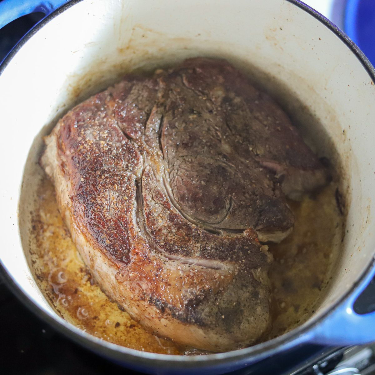 a chuck roast being seared in a dutch oven.