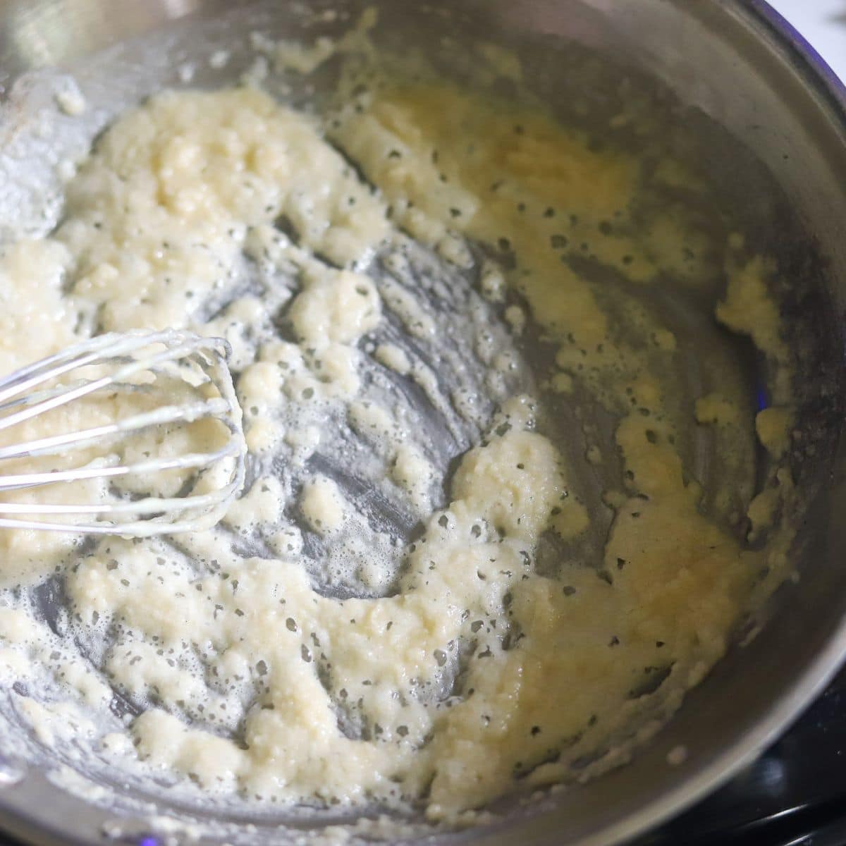 flour being whisked into melted butter to make a roux