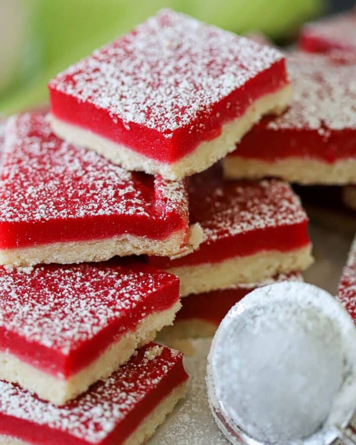 Cranberry bars dusted with powdered sugar and stacked up on a serving board