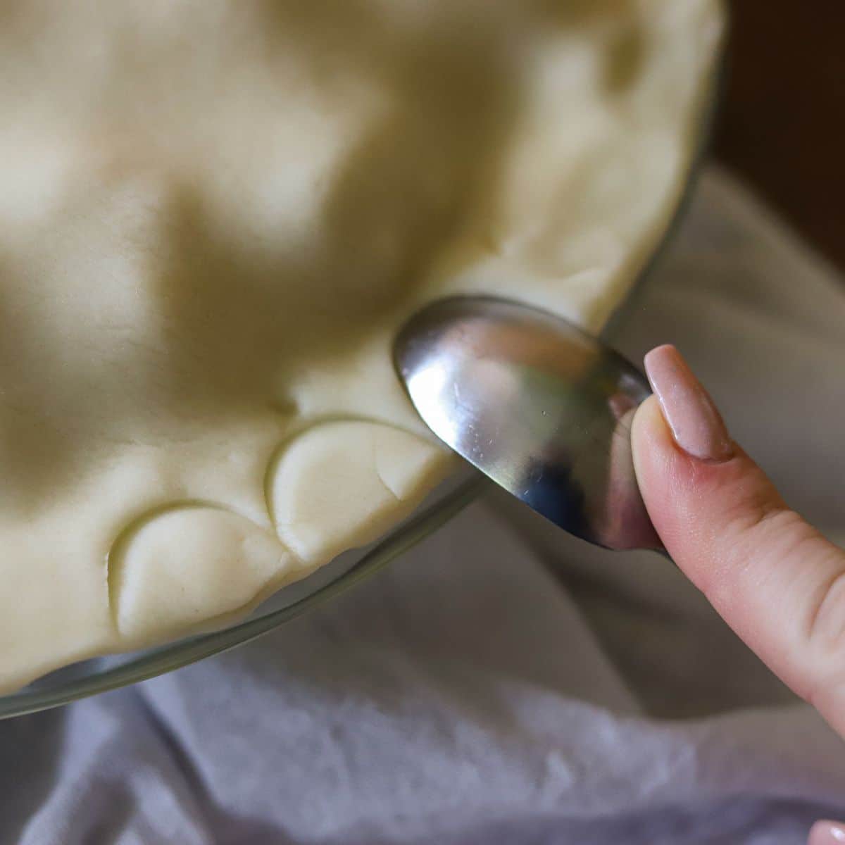 a pie crust being crimped with a spoon