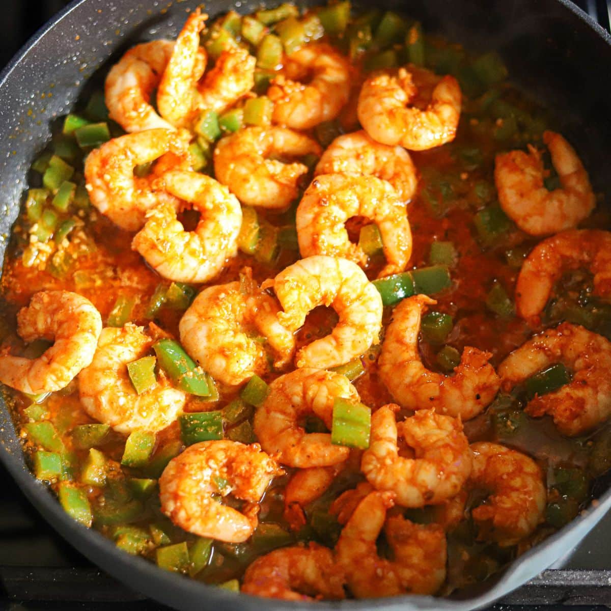 shrimp and green peppers cooking together in a skillet.