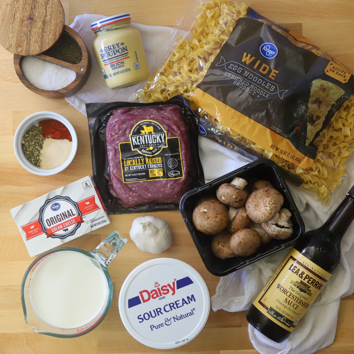 Ingredients for beef stroganoff with ground beef including ground beef, egg noodles, spices, milk, mushrooms, sour cream, cream cheese, and Worcestershire sauce