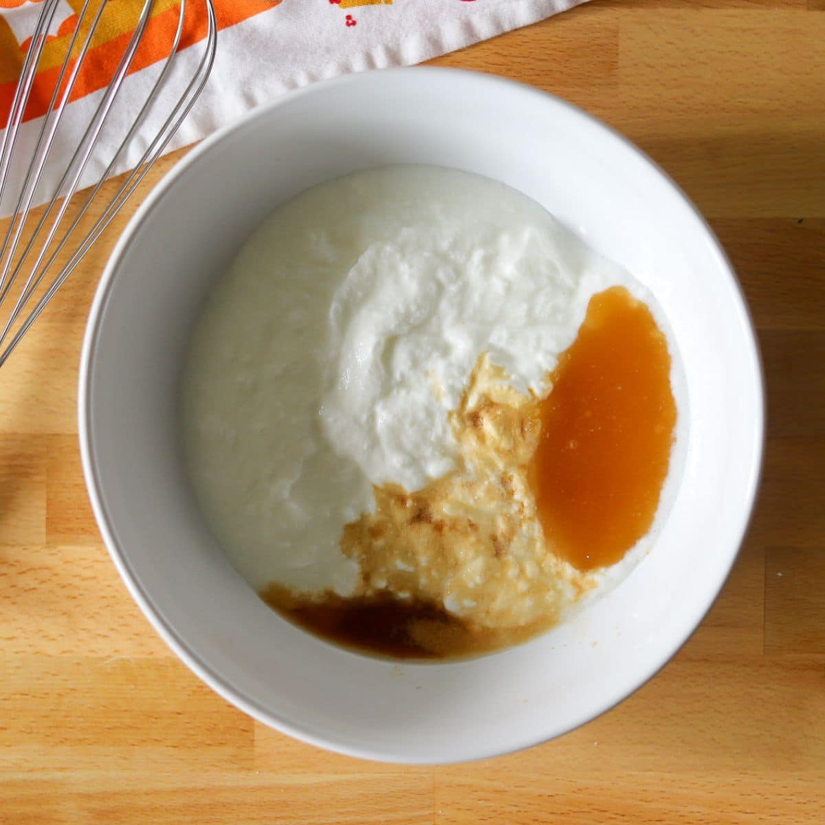 plain yogurt, honey, almond extract, and vanilla extract in a white bowl.