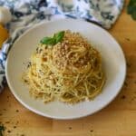 a plate full of lemony angel hair pasta topped with garlic breadcrumbs and a sprig of basil