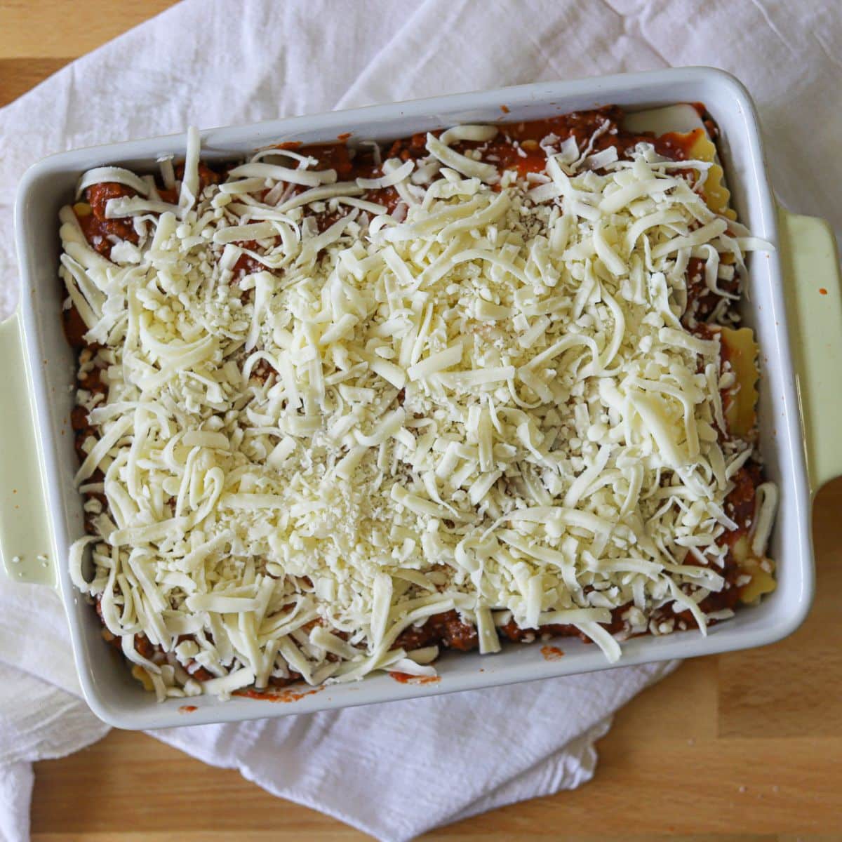 a baked ravioli topped with shredded cheese.