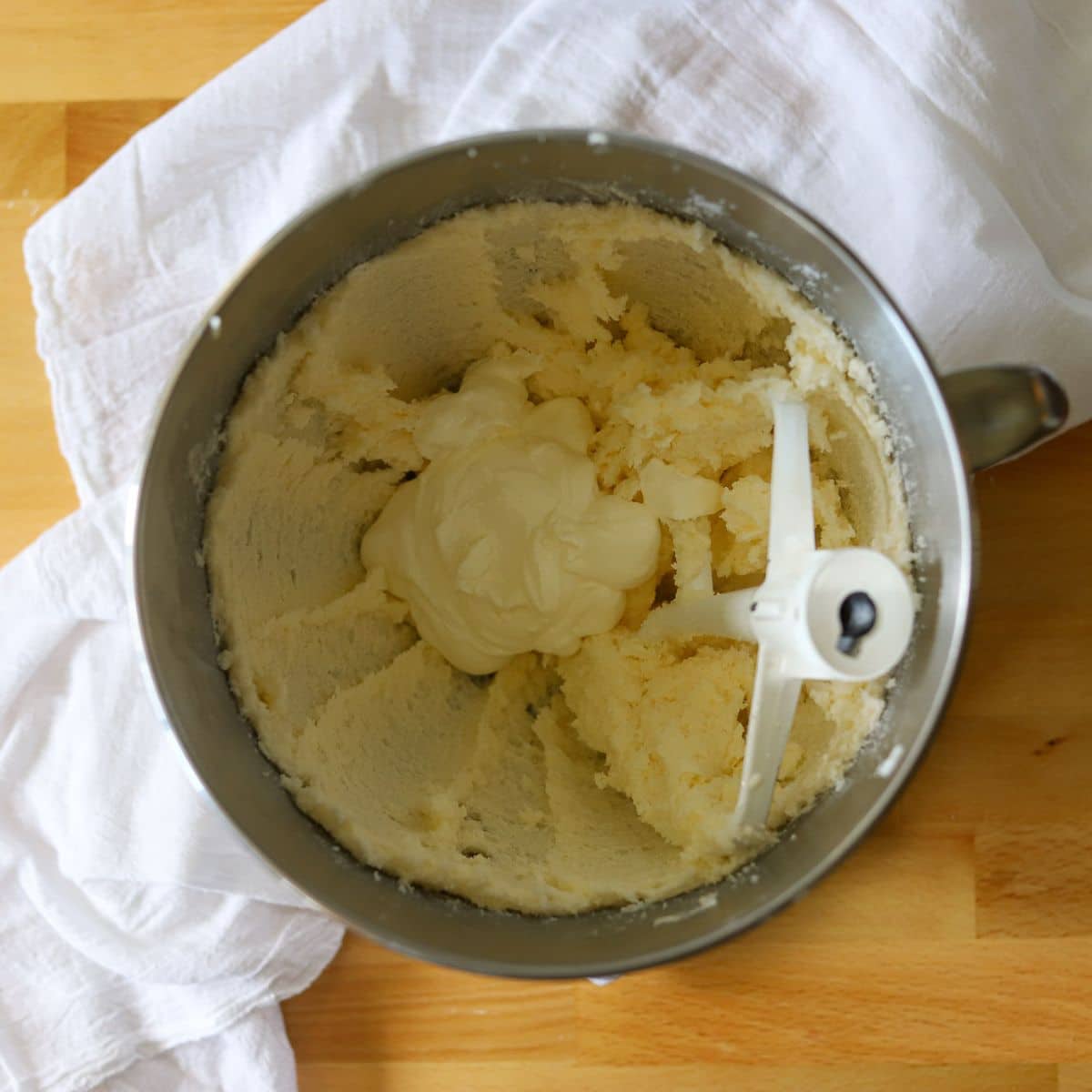 sour cream pound cake batter being prepared in a silver mixing bowl with a kitchen aid paddle