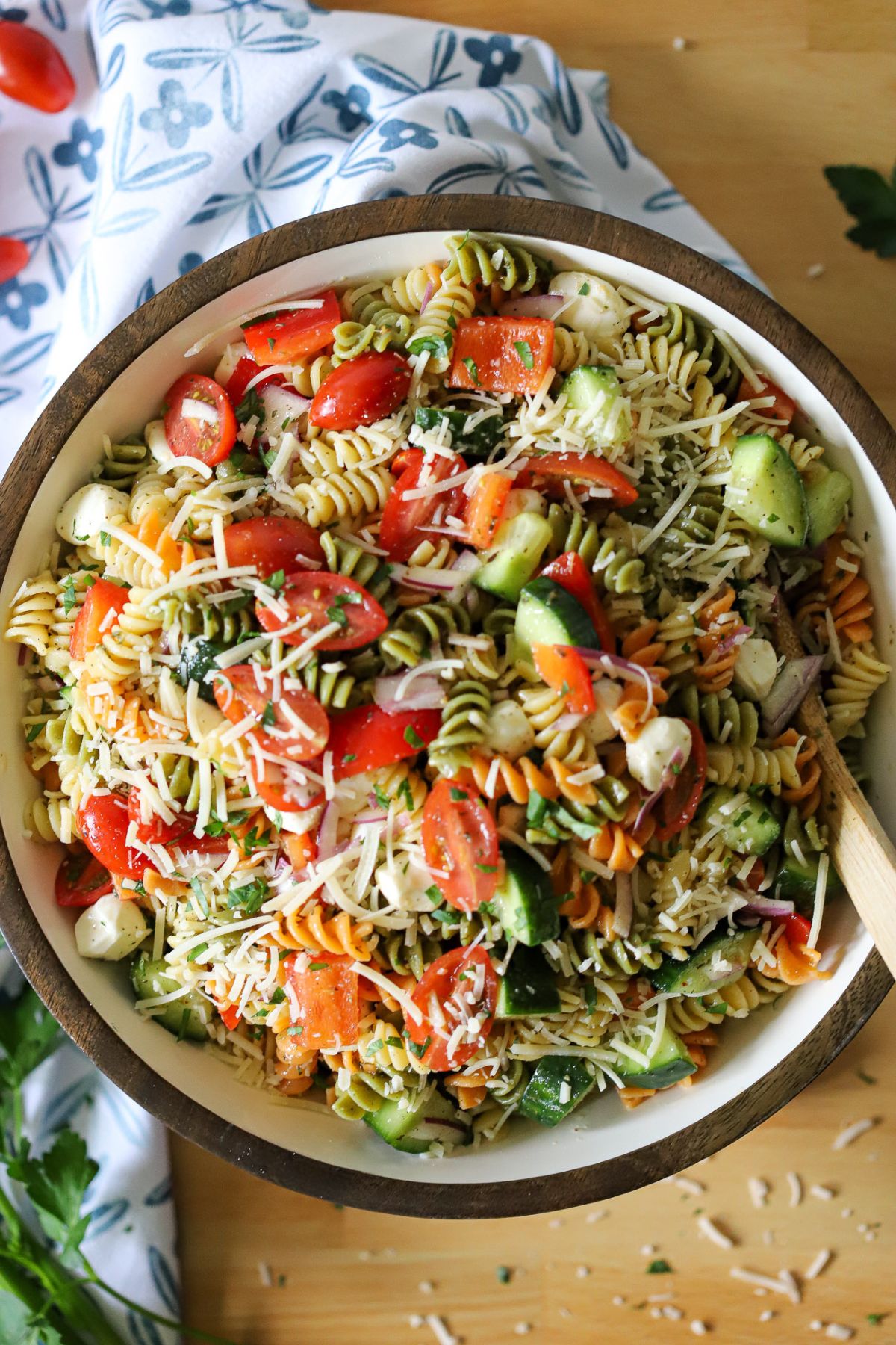 a large bowl of homemade zesty pasta salad made with tricolor rotini, cucumbers, tomatoes, onion, bell pepper and fresh mozzarella cheese