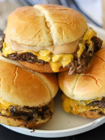 a stack of smash burgers with cheese and burger sauce on a white plate