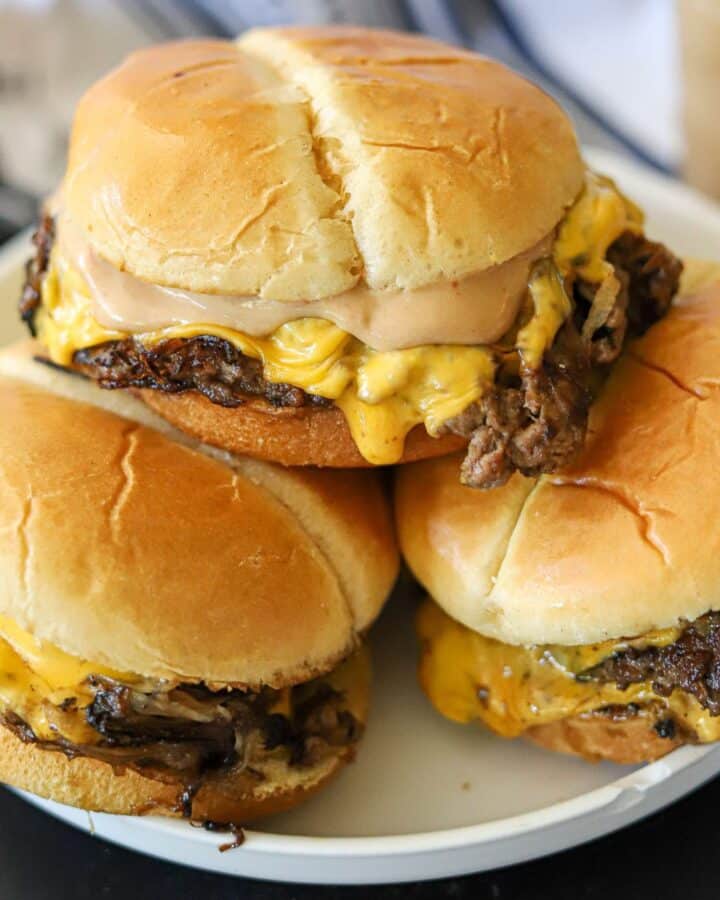 a stack of smash burgers with cheese and burger sauce on a white plate
