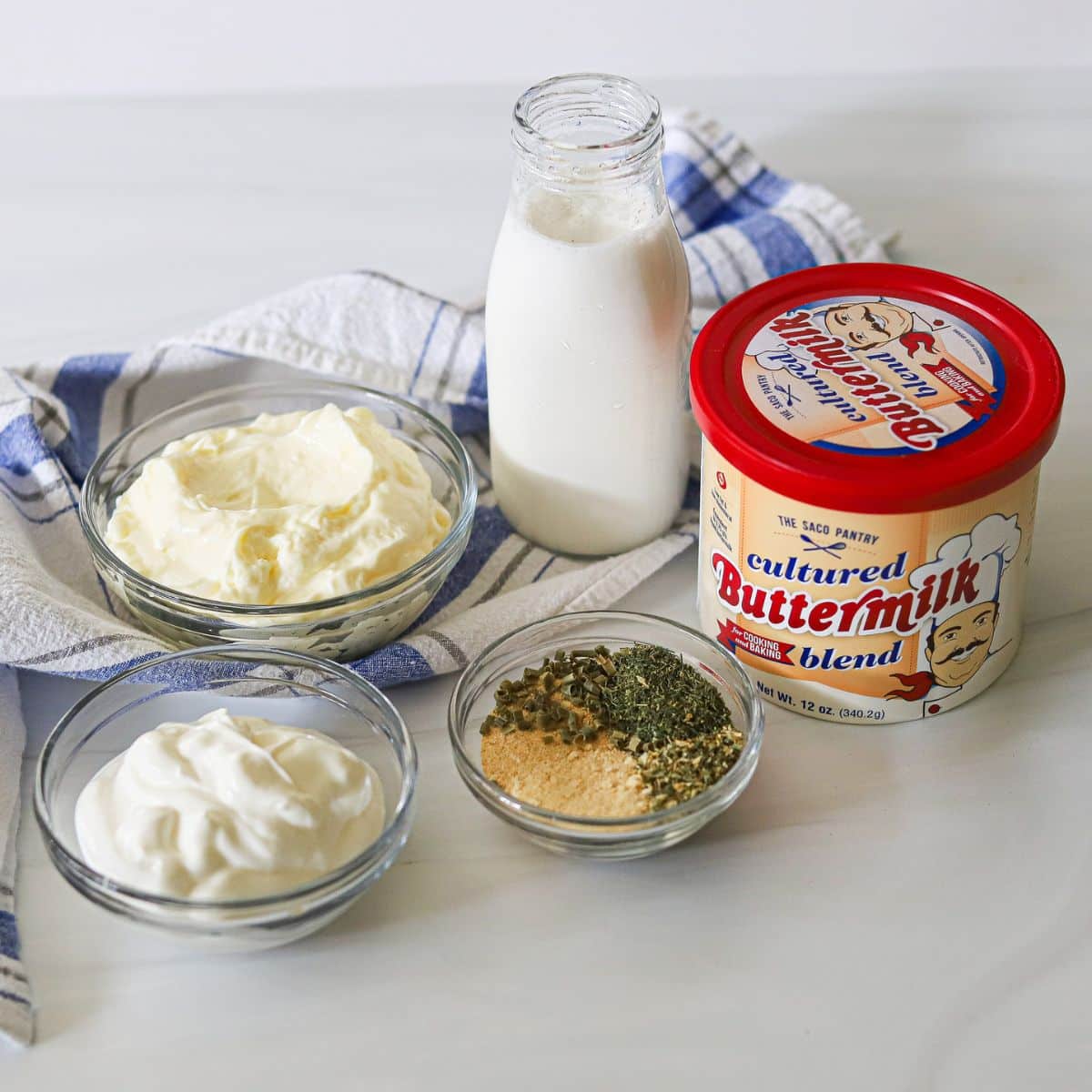 ingredients for homemade ranch dressing including powdered buttermilk, seasonings, sour cream, milk, and mayonnaise.